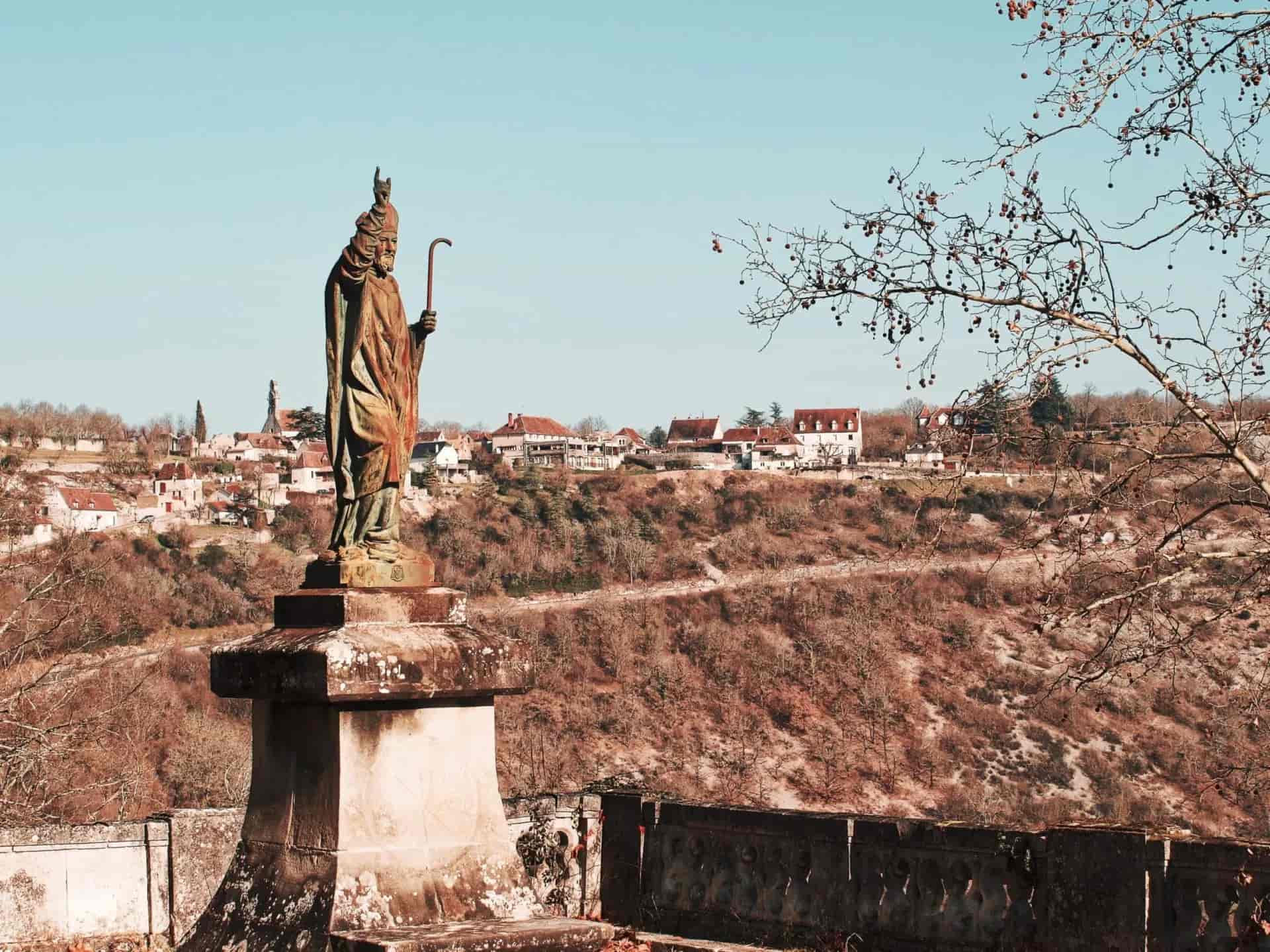 Statue of a bishop overlooking Rocamadour village and valley in Occitanie, France.