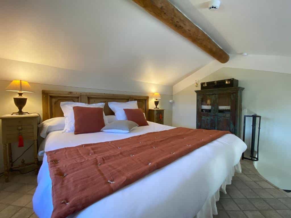 Bedroom with large bed, wooden headboard, and rustic cabinet under sloped ceiling.