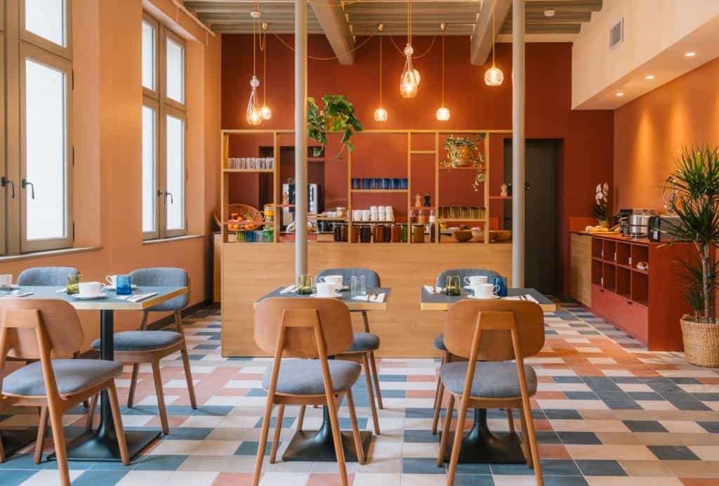 Dining area with wooden chairs, small tables, and a buffet counter against terracotta walls.