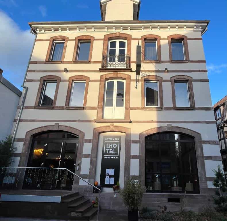 Hotel & Spa LHO TEL. building facade with stone trim and small balcony under blue sky.