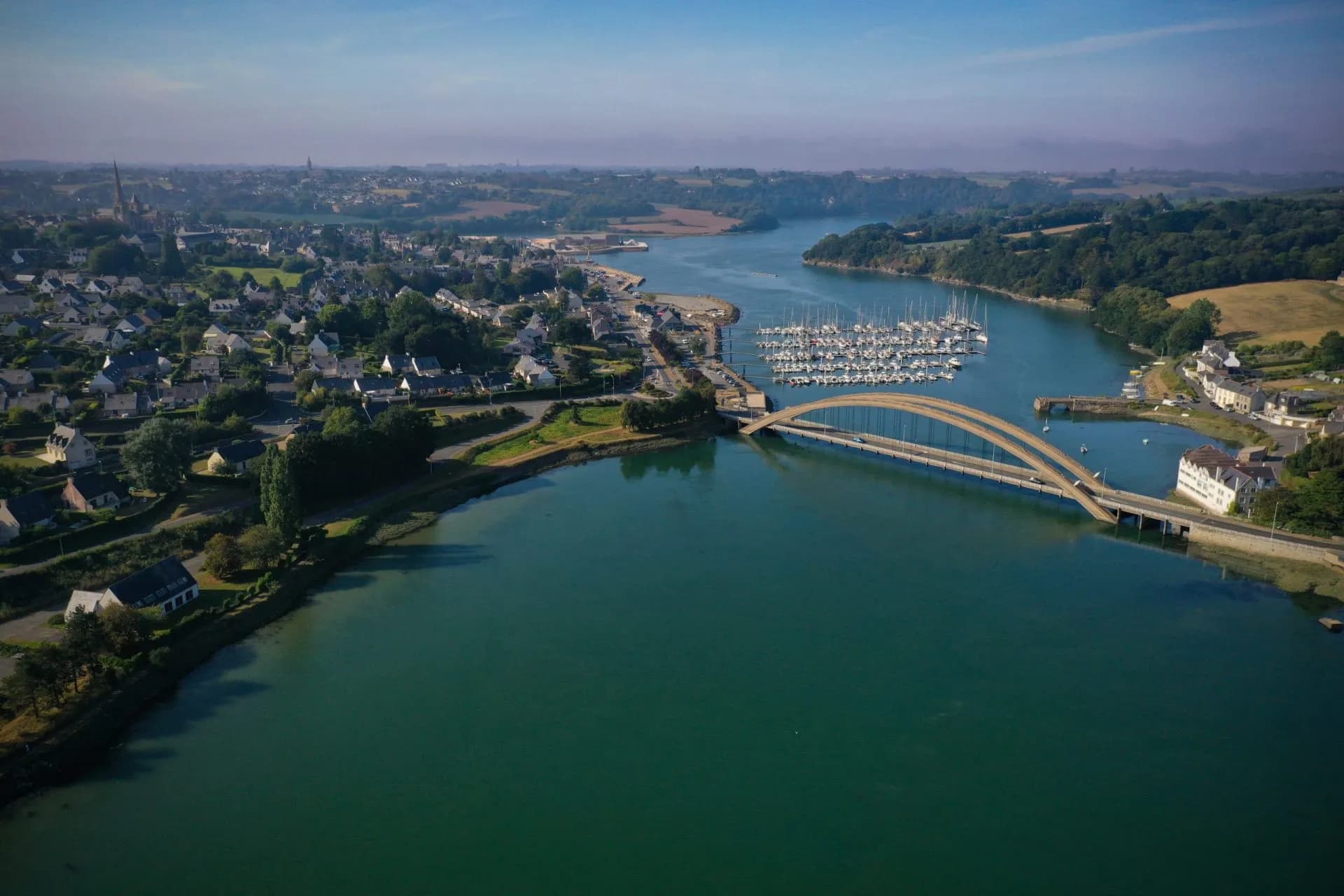 Arched bridge crossing river near marina and town in Treguier, France