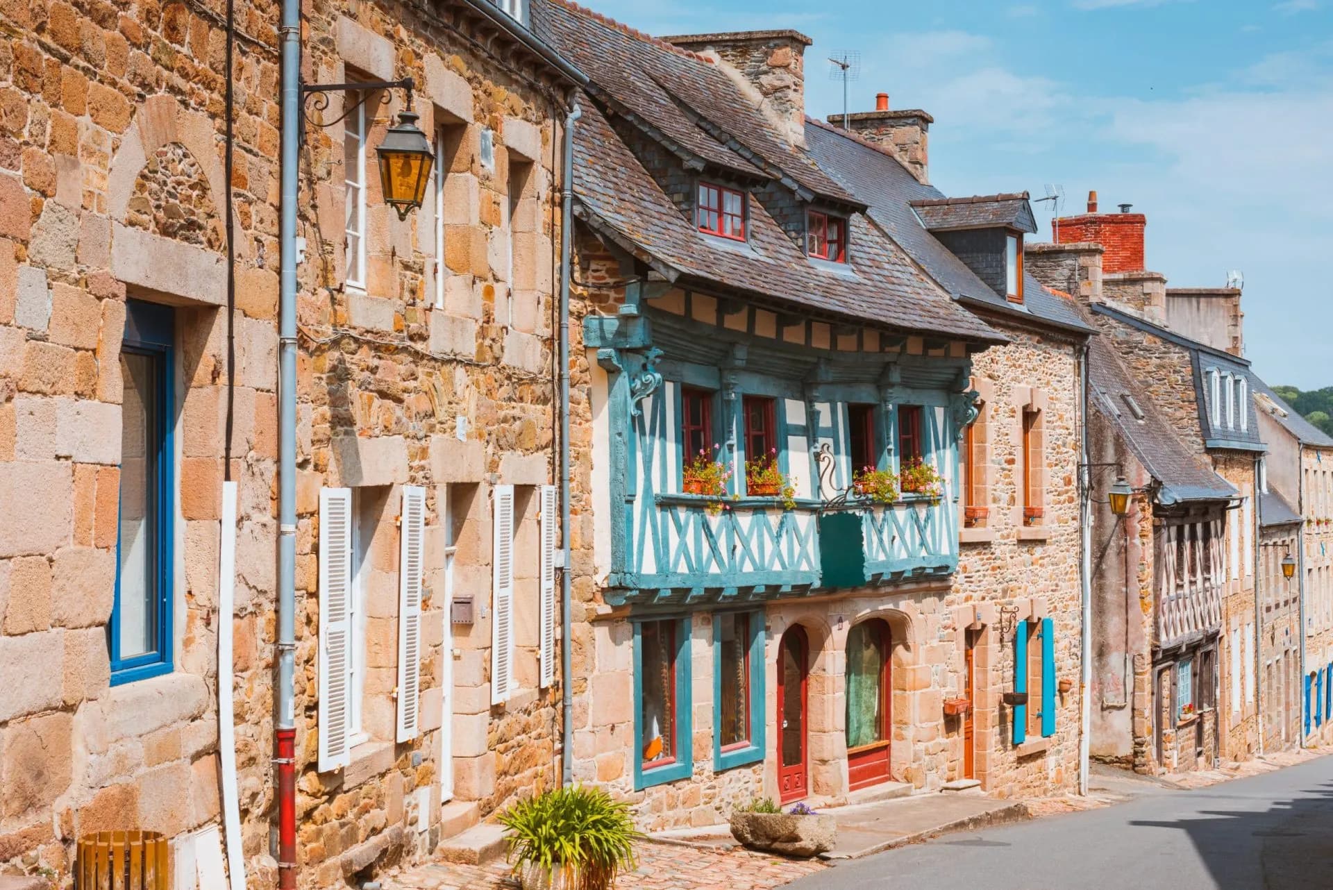 Stone and timber-framed houses line a street in the town of Tréguier under a blue sky.