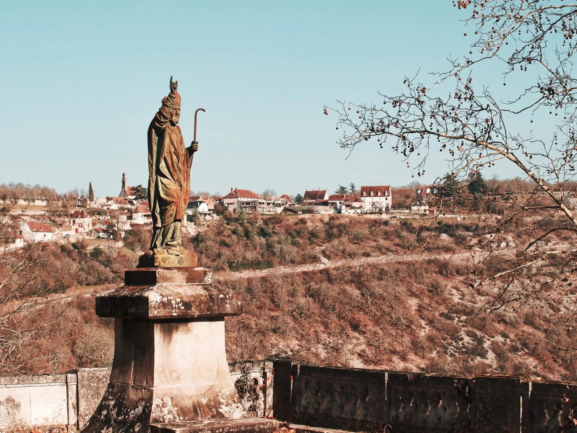 Statue of a bishop overlooking Rocamadour village and valley in Occitanie, France.