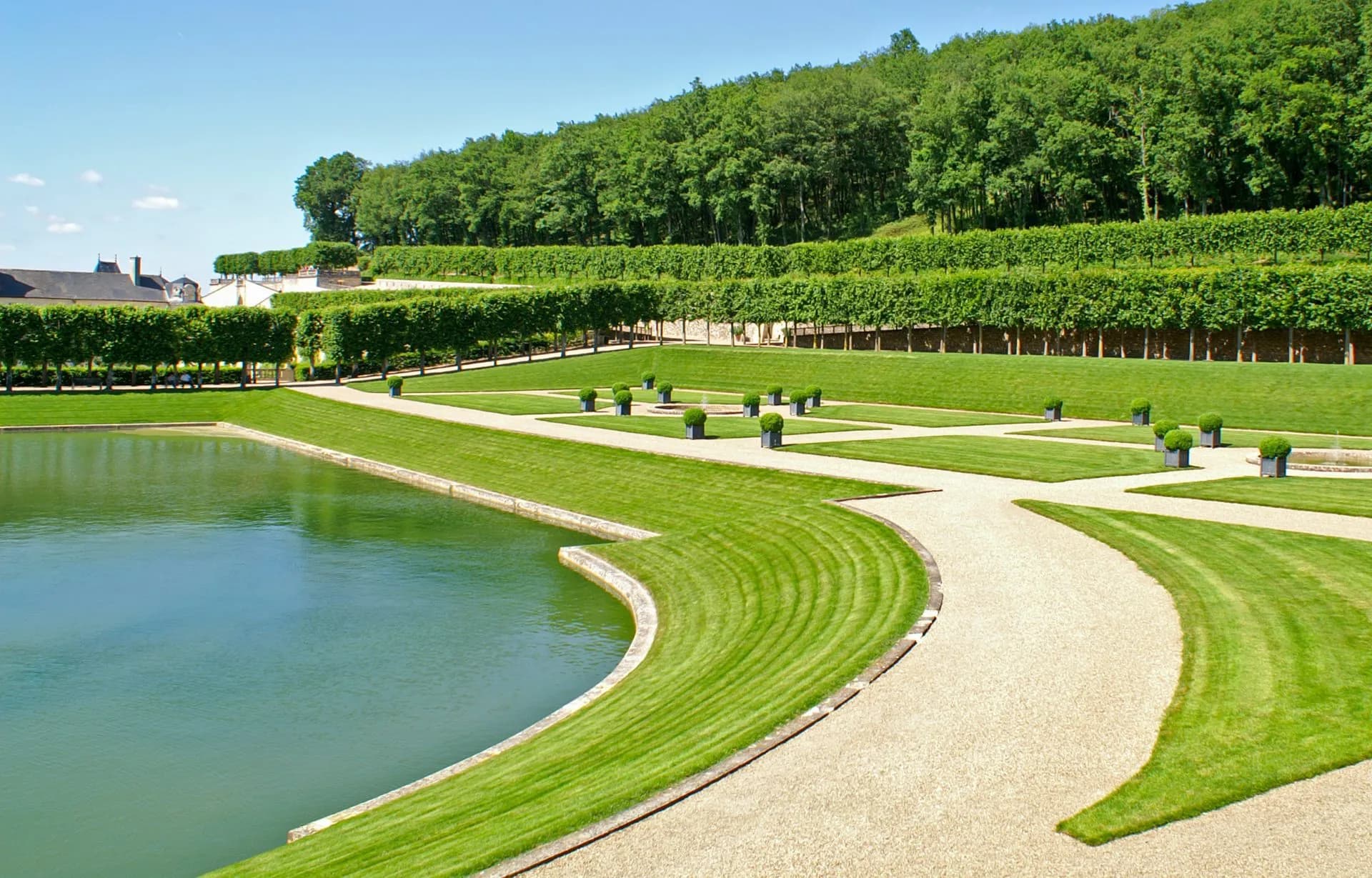 Formal gardens with manicured hedges, green lawns, gravel paths, and a reflecting pool at Villandry.