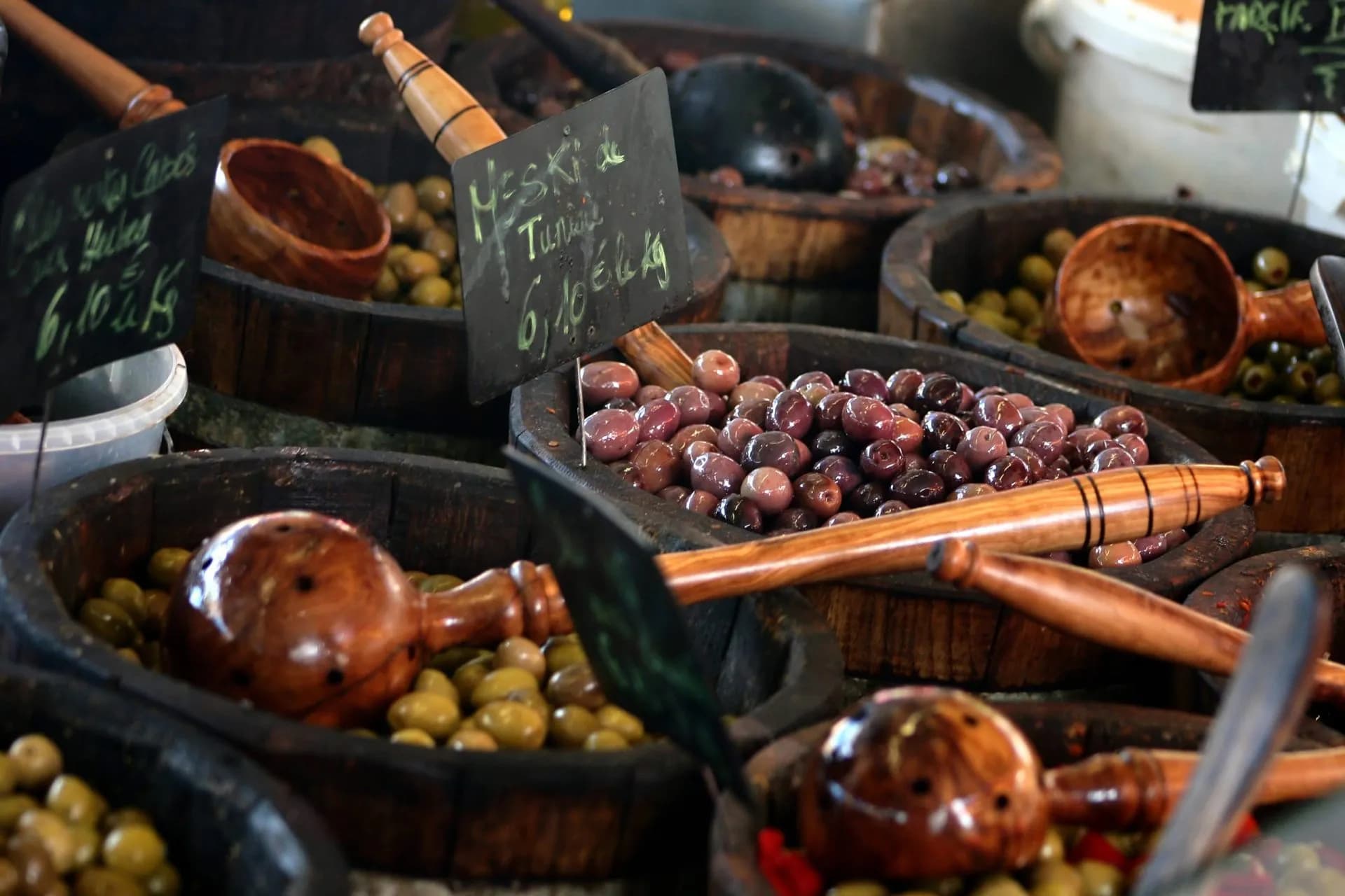 Olives in wooden barrels with wooden scoops and price signs at a market in Corsica