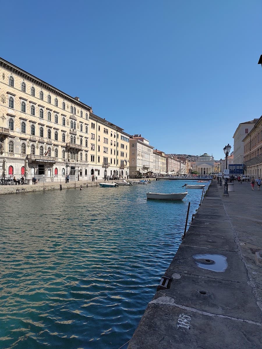 Canal with moored boats bordered by historic buildings and a stone walkway