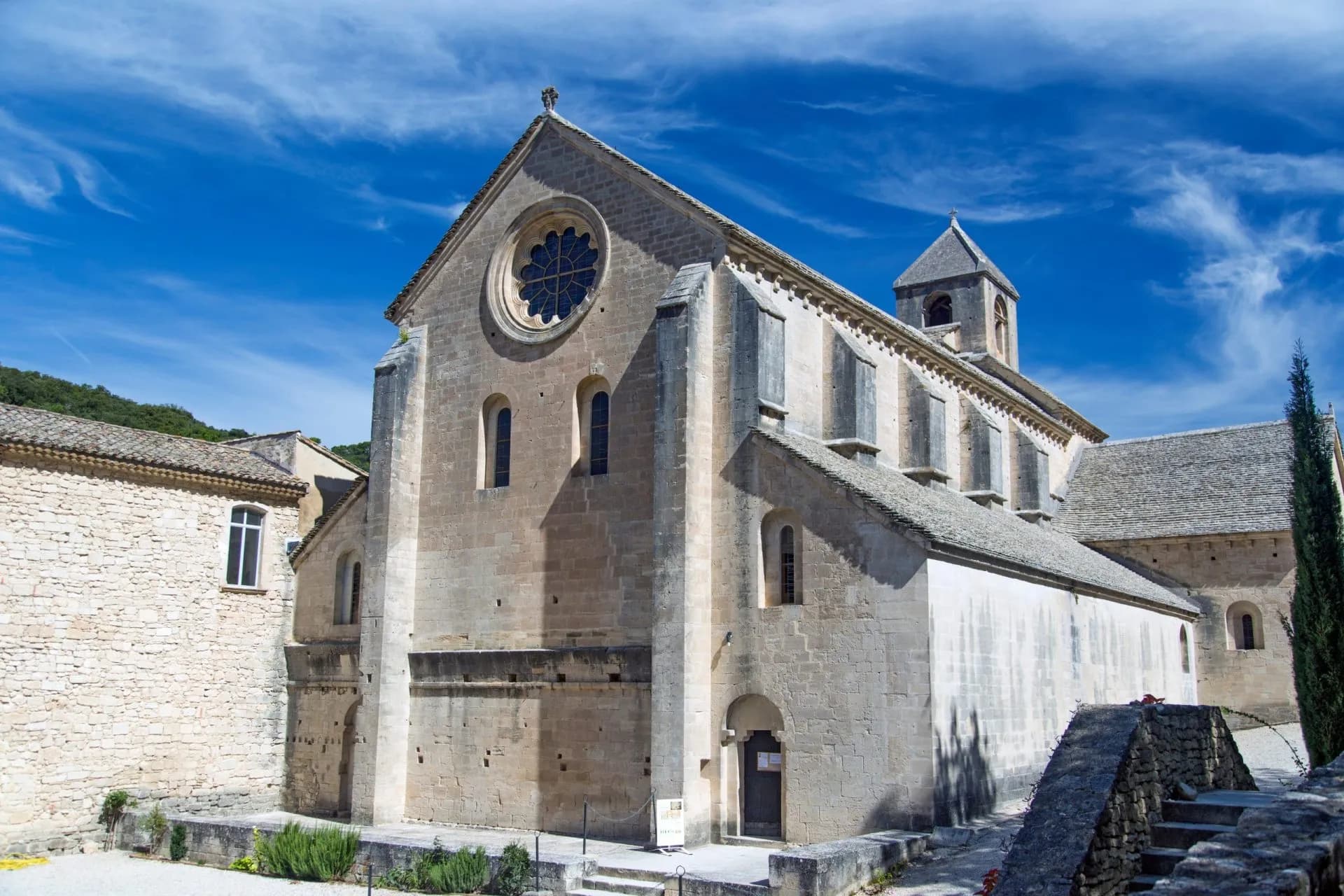Abbey of Sénanque stone church with rose window under bright blue sky