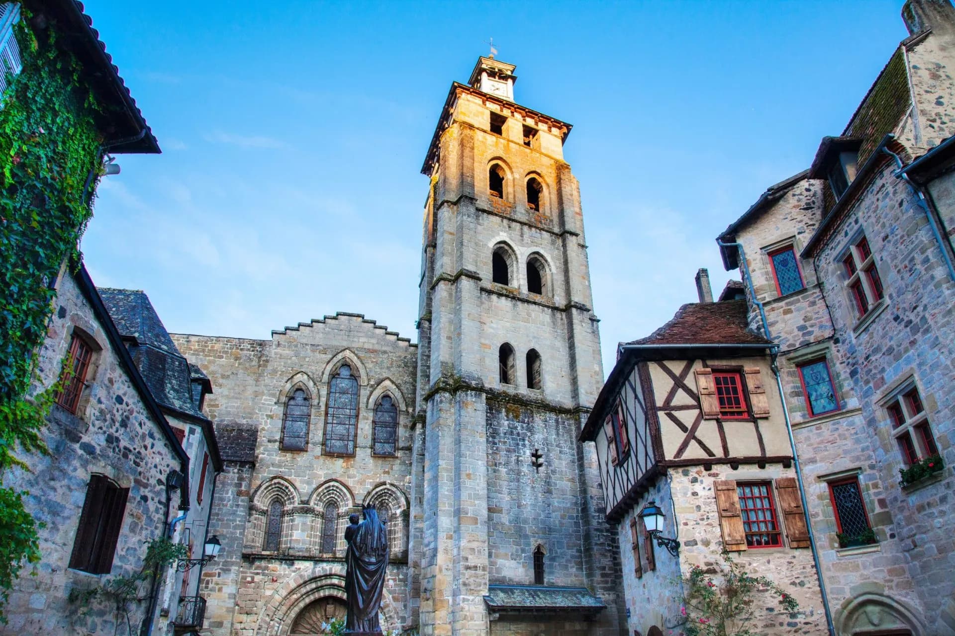 Stone church tower and historic buildings in Beaulieu-sur-Dordogne city centre.