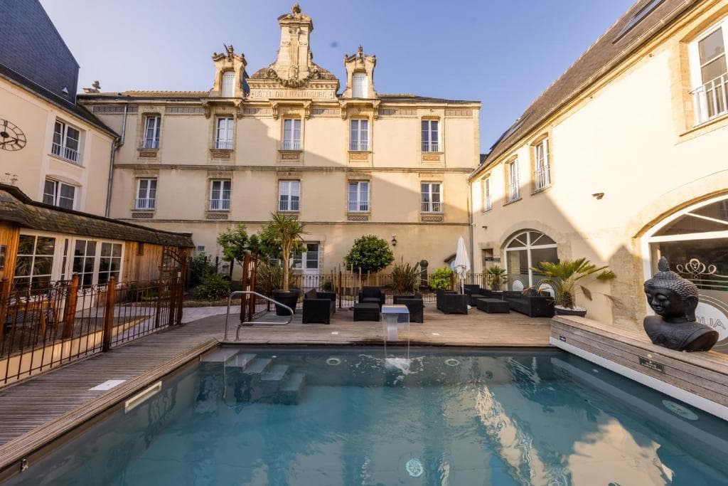 Outdoor pool and spa area with lounge seating between historic buildings at Hôtel de Brunville & Spa.