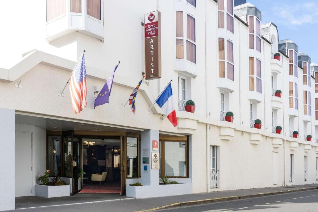 Best Western Plus L'Artist Hôtel exterior with US, EU, UK, and French flags flying.