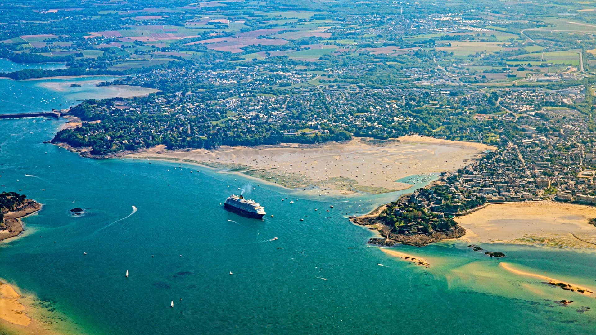 Aerial view of Saint-Malo and Cancale coastline, cruise ship in teal Atlantic Ocean water.