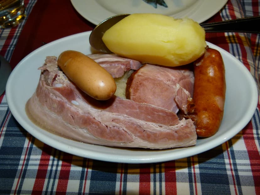 Choucroute garnie with sausages, cured meats, and boiled potato on a white dish