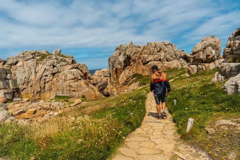 A young tourist walking the trails of Le Gouffre de Plougrescant, Cote de Granit Rose, Cotes d'Armor, Brittany, France